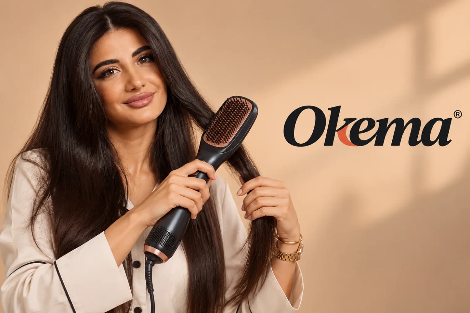 A model smiles while drawing an Okema heated straightening brush through long dark hair, against a warm sand backdrop with palm shadows.